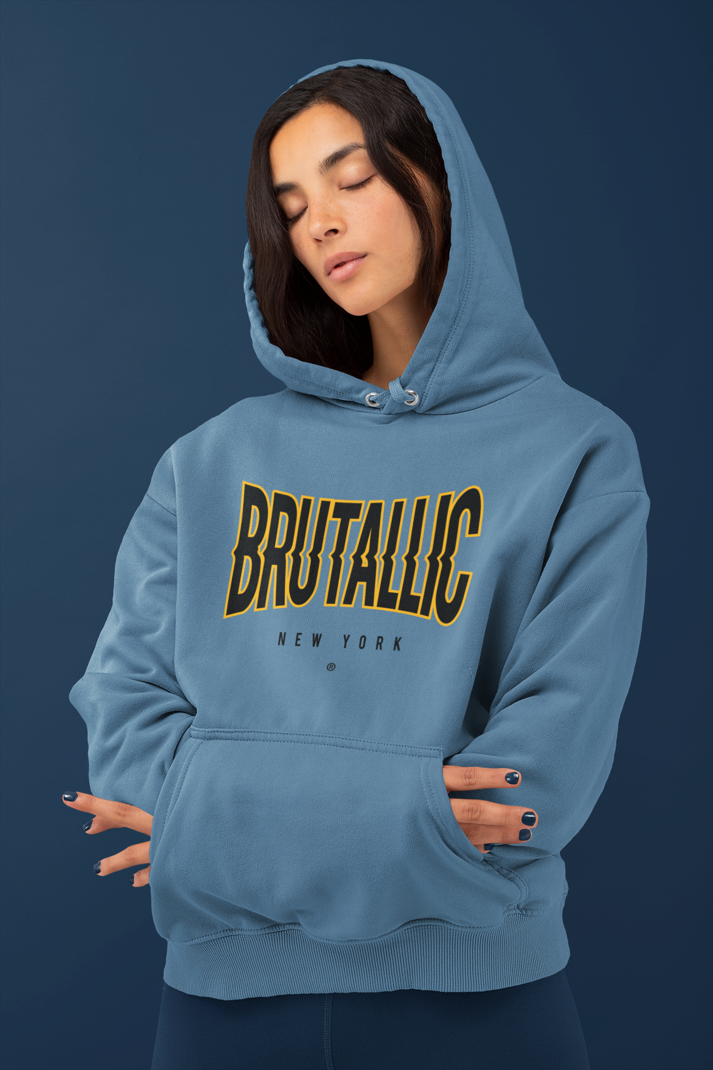 Indigo blue hoodie with disrupted brutallic front logo, worn by female model with hands tucked inside front pouch pocket
